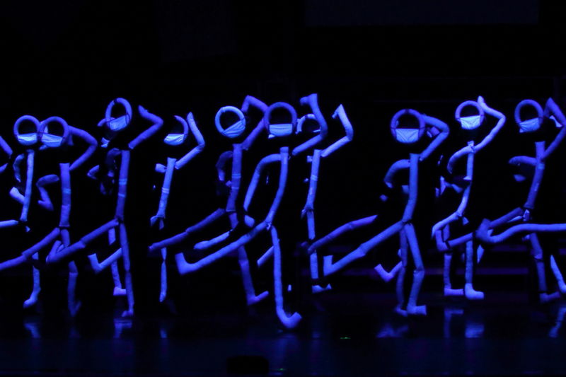 Stage design special effects with UV lighting and specialized costumes on dancers